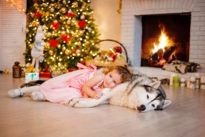 девочка и собака лайка лежат на теплом полу у горящего камина