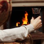 мужчина с бокалом вина у камина